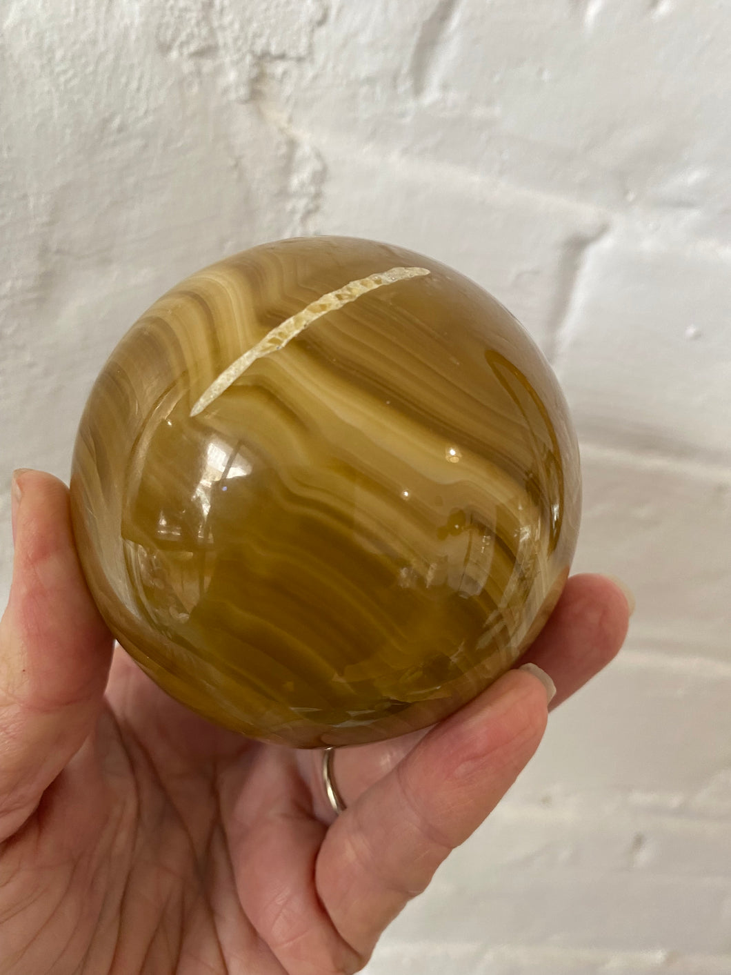 Honey Calcite Crystal Sphere against white wall